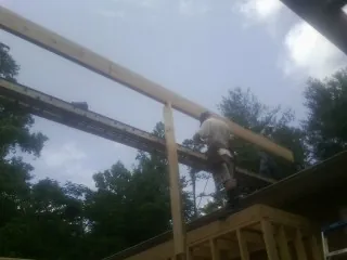 Carpenter setting a ridge beam over a new addition frame — Ice Dam Removal by Roofing Brothers in Coloma