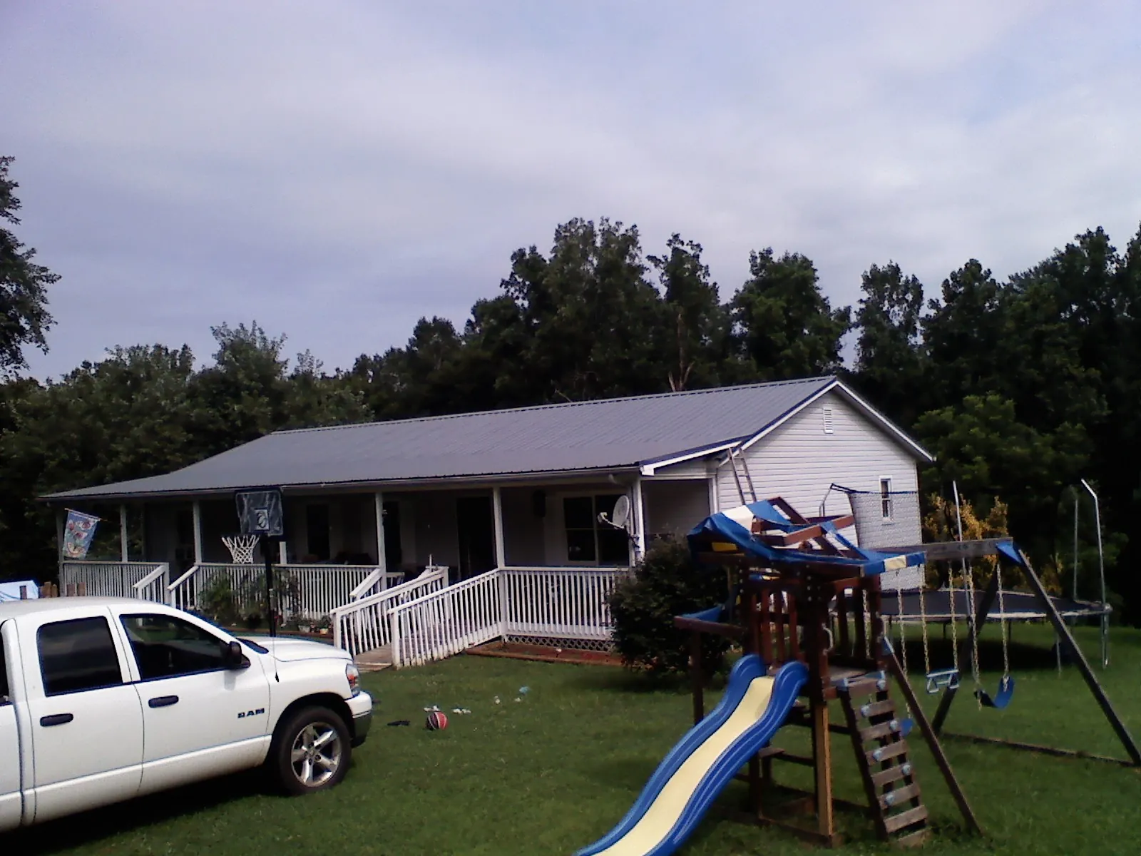 Dark metal roof on a country home with a full length front porch in Coloma