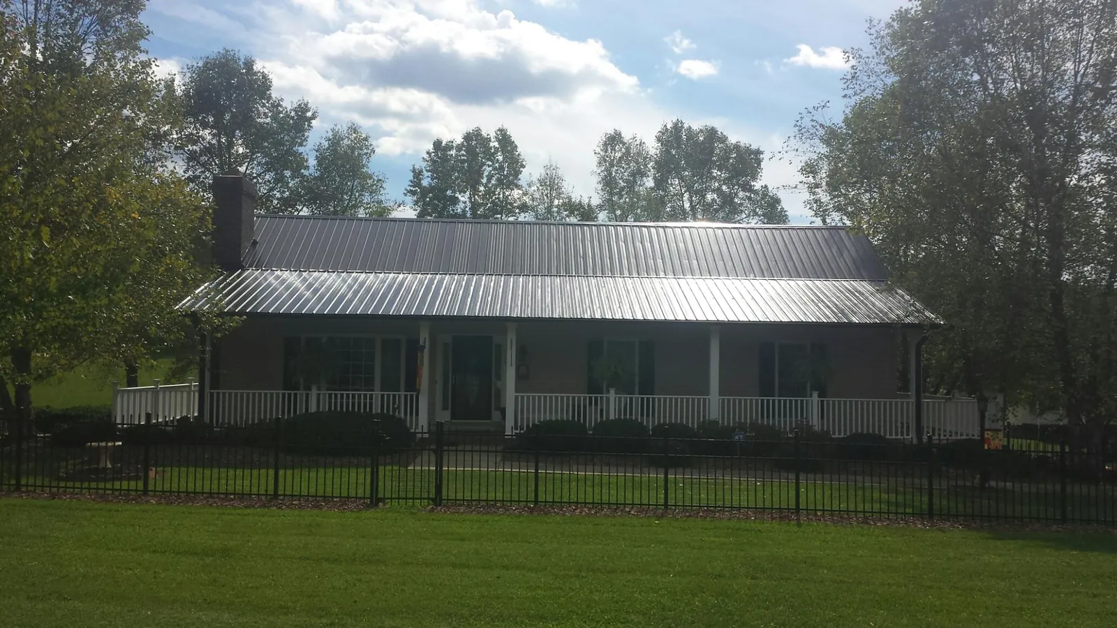 Gray metal roof on a brick ranch with a full width front porch — Gutter Guard Installation work by our crew in Coloma