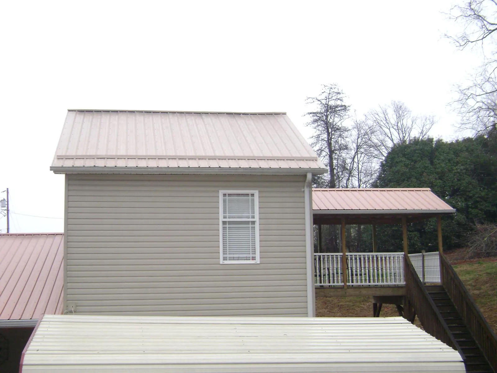Tan metal roofs on a two story addition and attached porch, from a Roof Replacement job in Coloma
