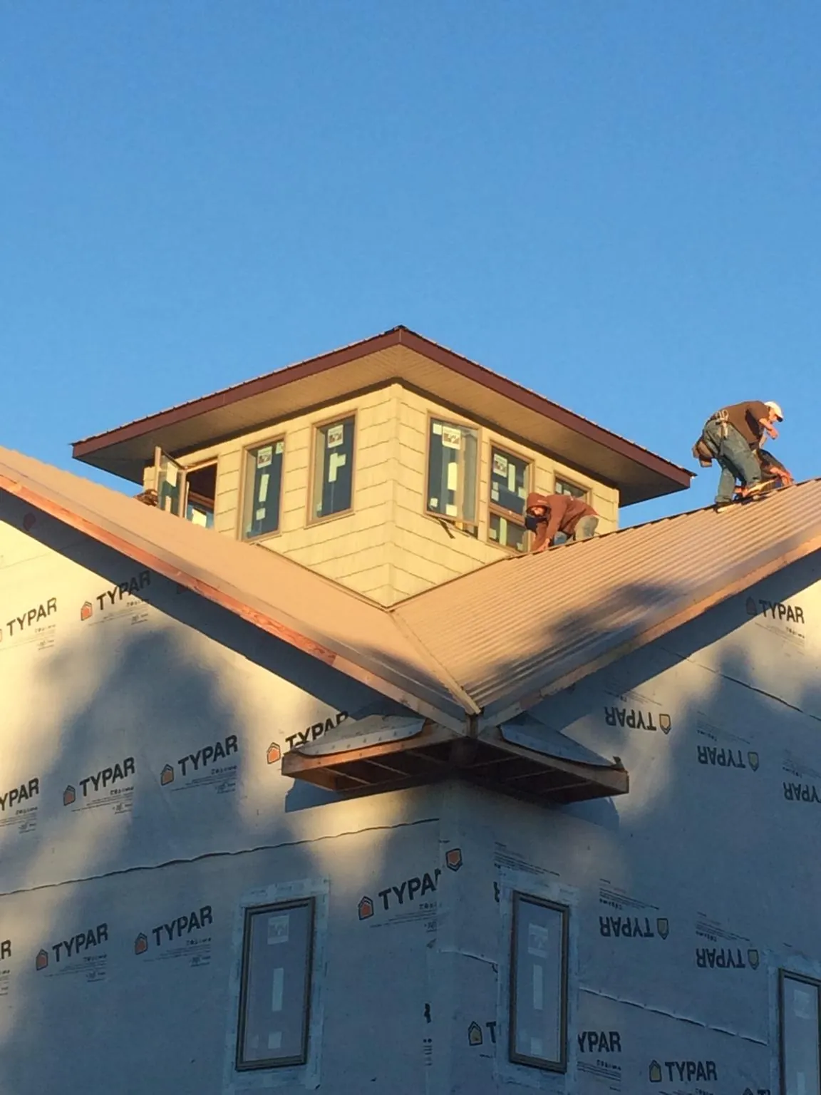 Roofers working around a rooftop cupola on a new metal roof at sunset — Roof Waterproofing in Coloma by Roofing Brothers